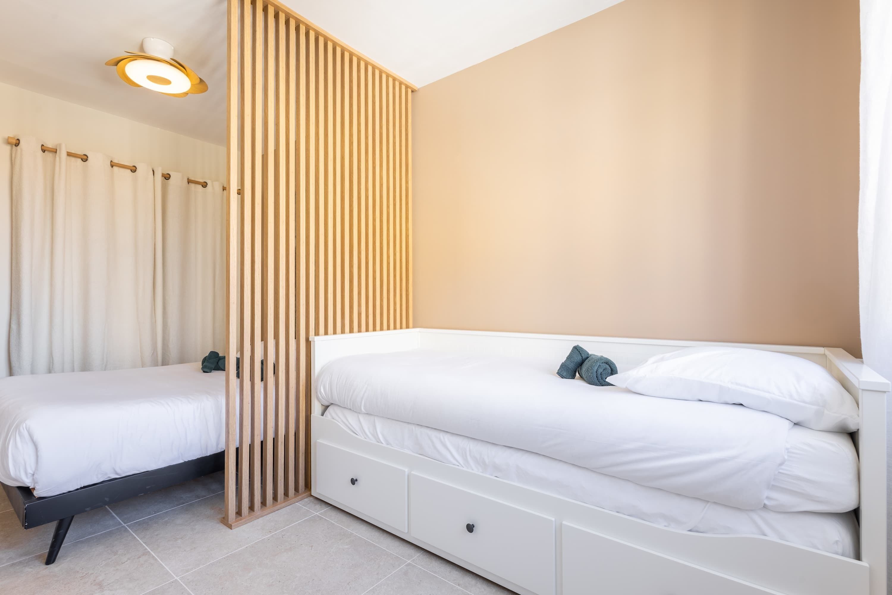 A bedroom with a bed, a bedside table, a nightstand, and a ceiling light fixture.