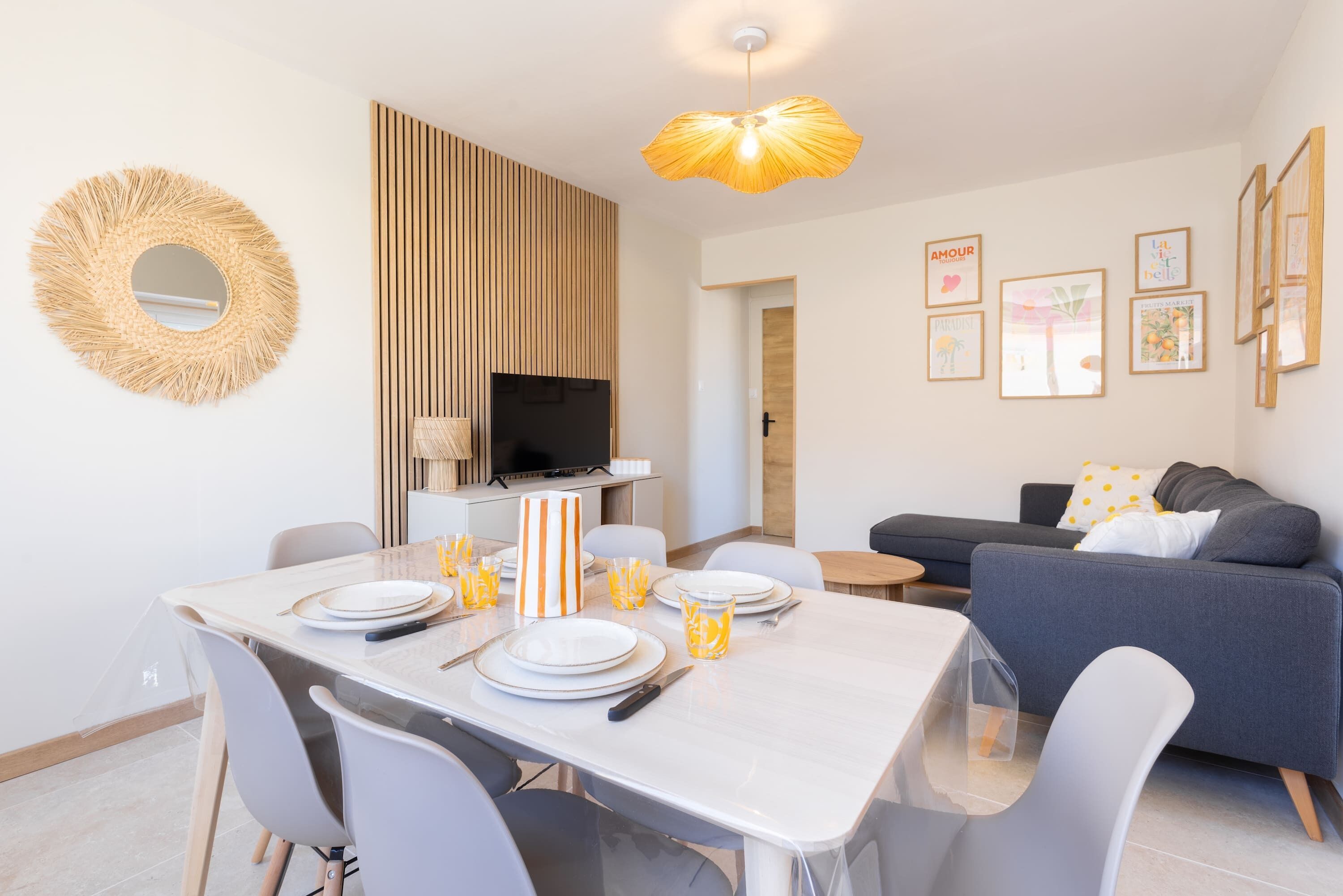 A modern living room with a dining area, a television, and framed artwork on the walls.