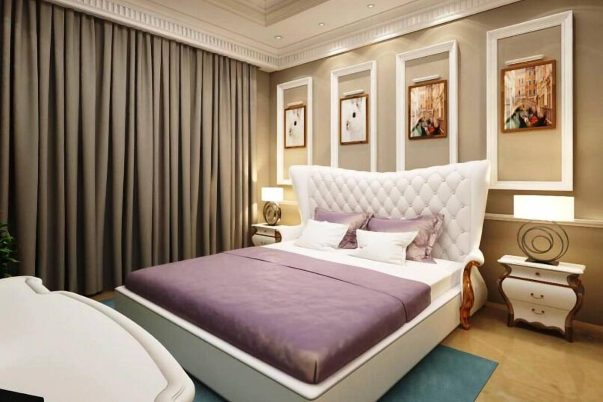 A bedroom with a large bed, a nightstand, a dresser, and a wall with framed pictures.