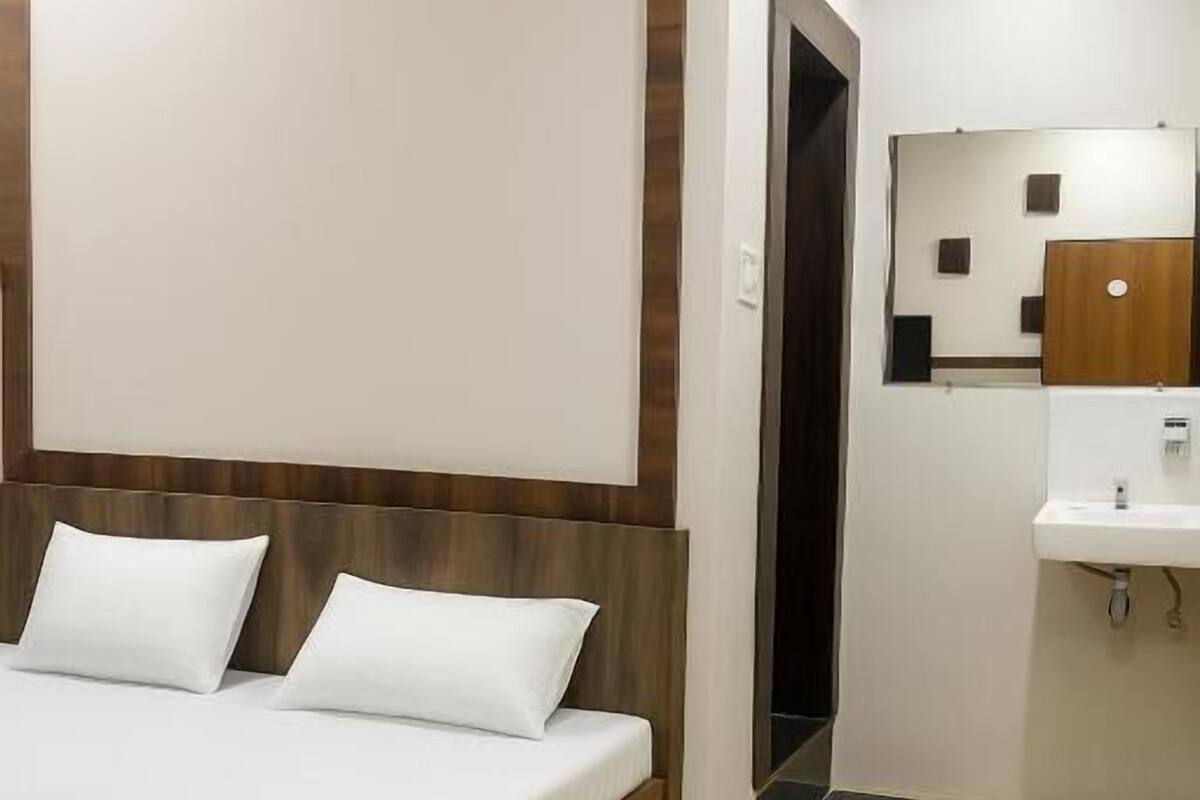 A hotel room with a bed, a small bathroom with a sink, and a mirror.