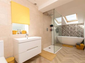 Ein modernes Badezimmer mit Duschkabine aus Glas, freistehender Badewanne und Waschtisch mit Spiegel.