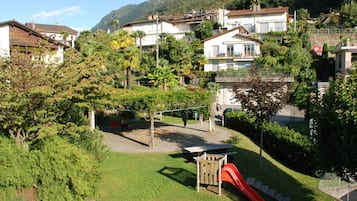 Bairro residencial com casas, um parquinho com escorrega e uma montanha ao fundo.