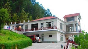 A two-story building with a balcony, a covered entrance, and a vehicle parked in front.