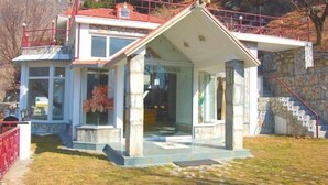 A two-story building with a stone facade, a red roof, and a glass entrance.