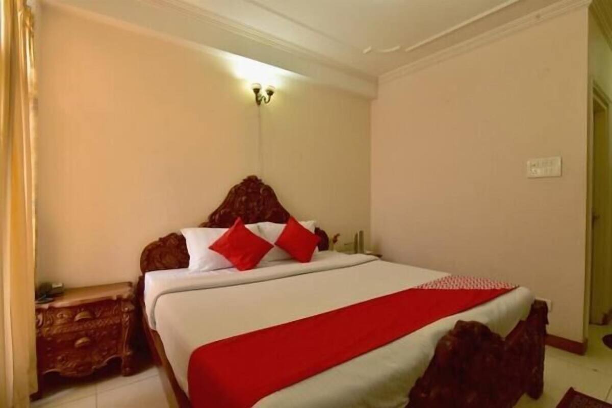 Un dormitorio con cama, mesita de noche, lámpara de pared y puerta.