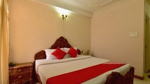 A bedroom with a bed, a nightstand, a wall-mounted light fixture, and a door.