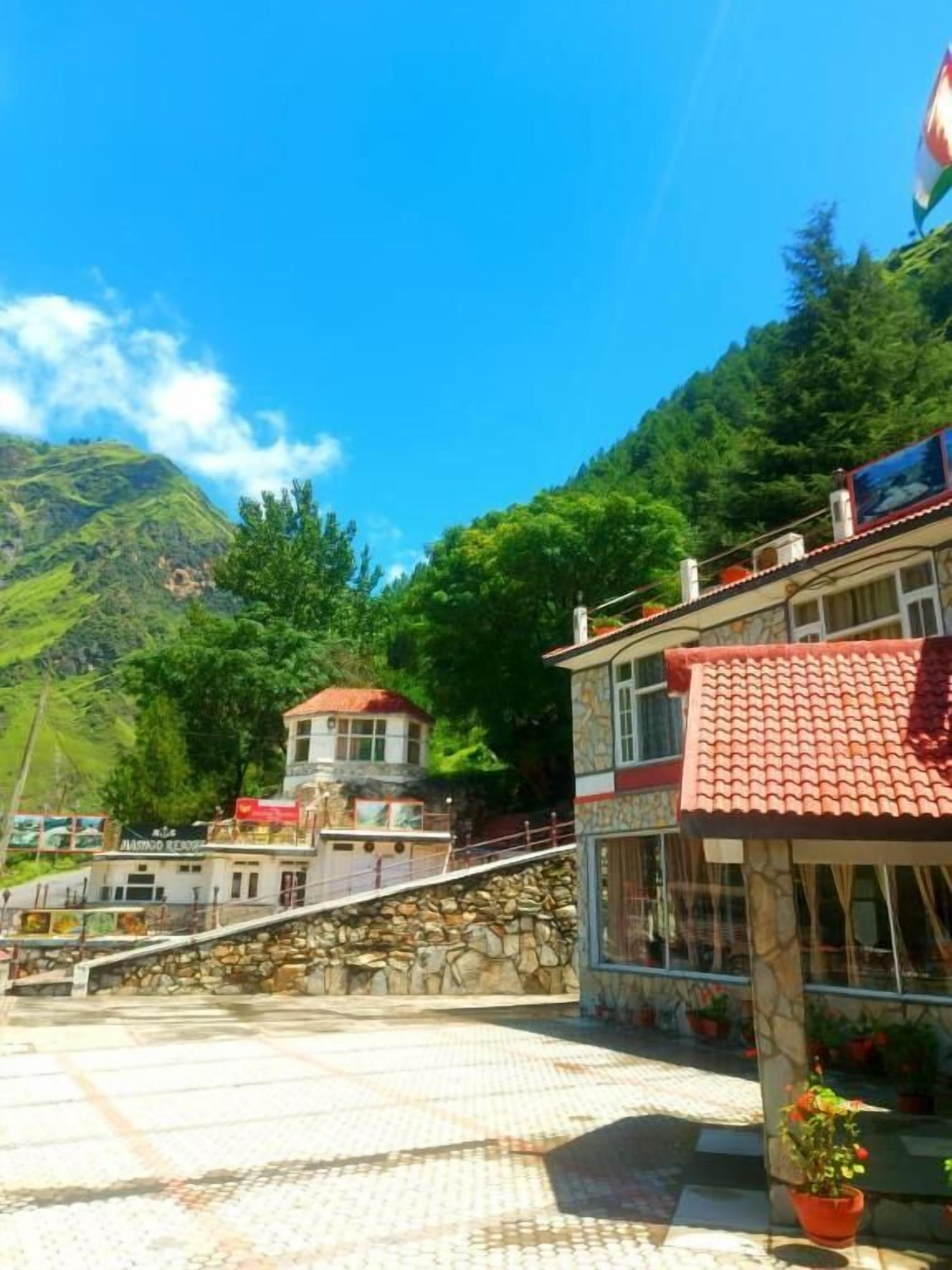 Ein Hotel mit einer Steintreppe, einem roten Ziegeldach und einem Berg im Hintergrund.