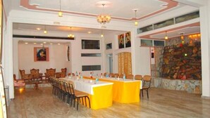 A spacious dining area with a high ceiling, chandeliers, and a stone wall with a fireplace.
