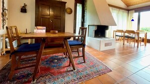 A dining area with a wooden table, chairs, a rug, and a fireplace. - Casa Poggio Verde by Interhome (Magadino)