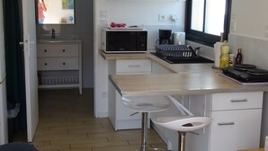 A compact kitchen with a microwave, coffee maker, and bar stools. - Cosy & quiet studio with private parking, near ocean and town center. (La Rochelle 17000)