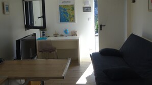 A room with a desk, a chair, a bed, a TV, a map, and a mirror. - Cosy & quiet studio with private parking, near ocean and town center. (La Rochelle 17000)