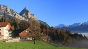 Eine Berglandschaft mit einem Haus und blauem Himmel.