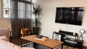 Un salon moderne avec un canapé, une table basse, un téléviseur, une plante en pot et une affiche inspirante.