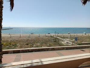 Ein Strand mit freiem Blick auf das Meer, einer Holzstege und einem Hinweisschild.