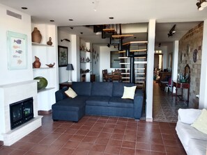 Ein Wohnzimmer mit einer Eckcouch, einem Kamin und einem Essbereich im Hintergrund.
