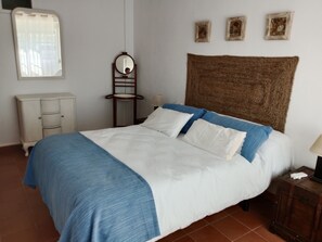 Une chambre à coucher comprenant un lit, une table de chevet, une commode, un miroir et trois tableaux encadrés accrochés au mur.