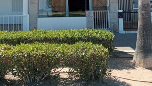 Um edifício de dois andares com varanda, portão e uma palmeira.