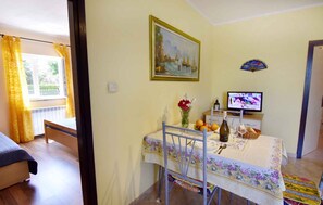 Habitació amb un llit, una taula de menjador amb un ram de flors, una televisió i un quadre a la paret.