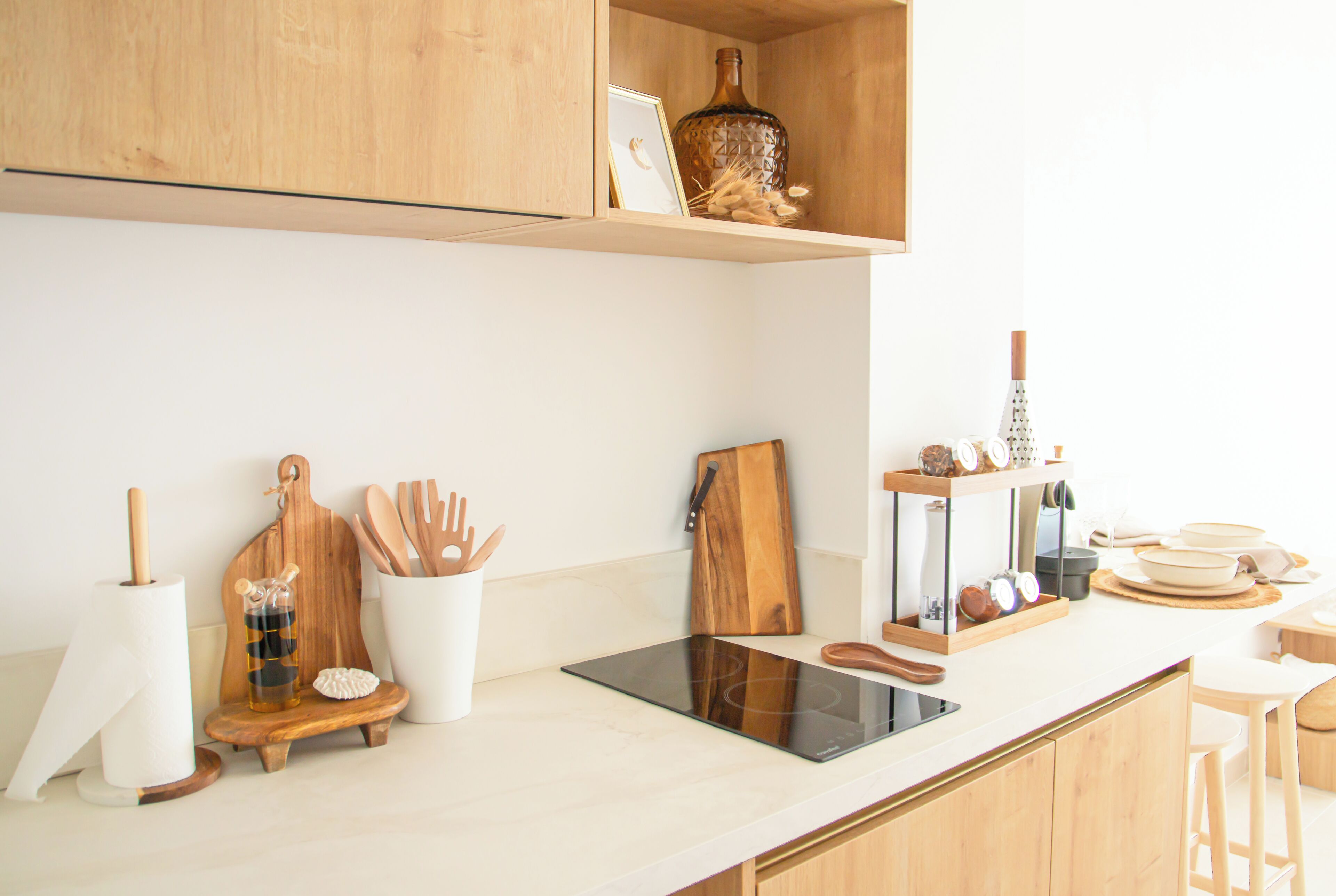 A kitchen with wooden cabinets, a countertop, a built-in stove, and various kitchen utensils.