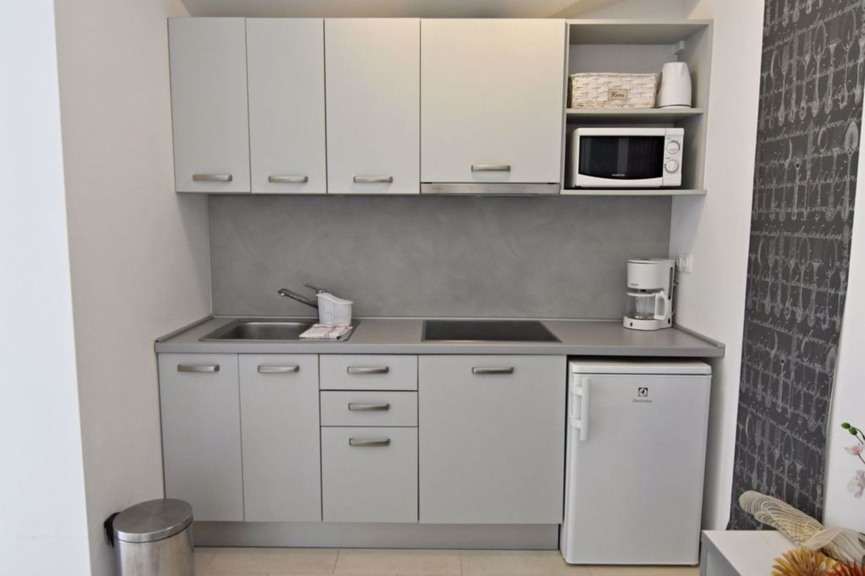 A compact kitchen with a microwave, coffee maker, and a small refrigerator.
