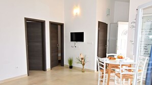 Ein modernes Wohnzimmer mit Flachbildfernseher, einem Esstisch mit Stühlen und einer Couch.