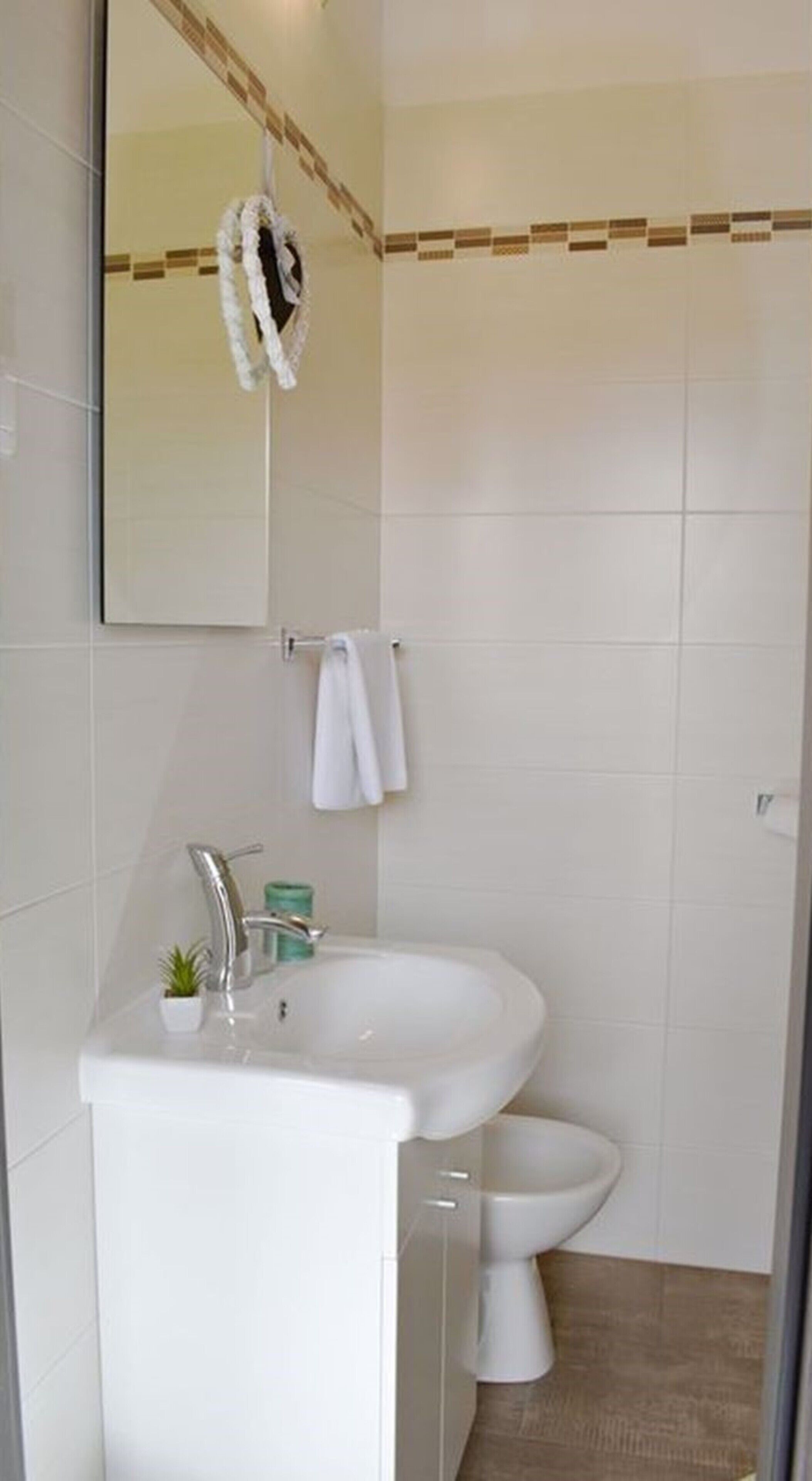 A bathroom with a white sink, a mirror, a towel rack, and a toilet.