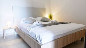 Ein modernes Schlafzimmer mit einem Holzbettgestell, weißer Bettwäsche und einer Nachttischlampe.