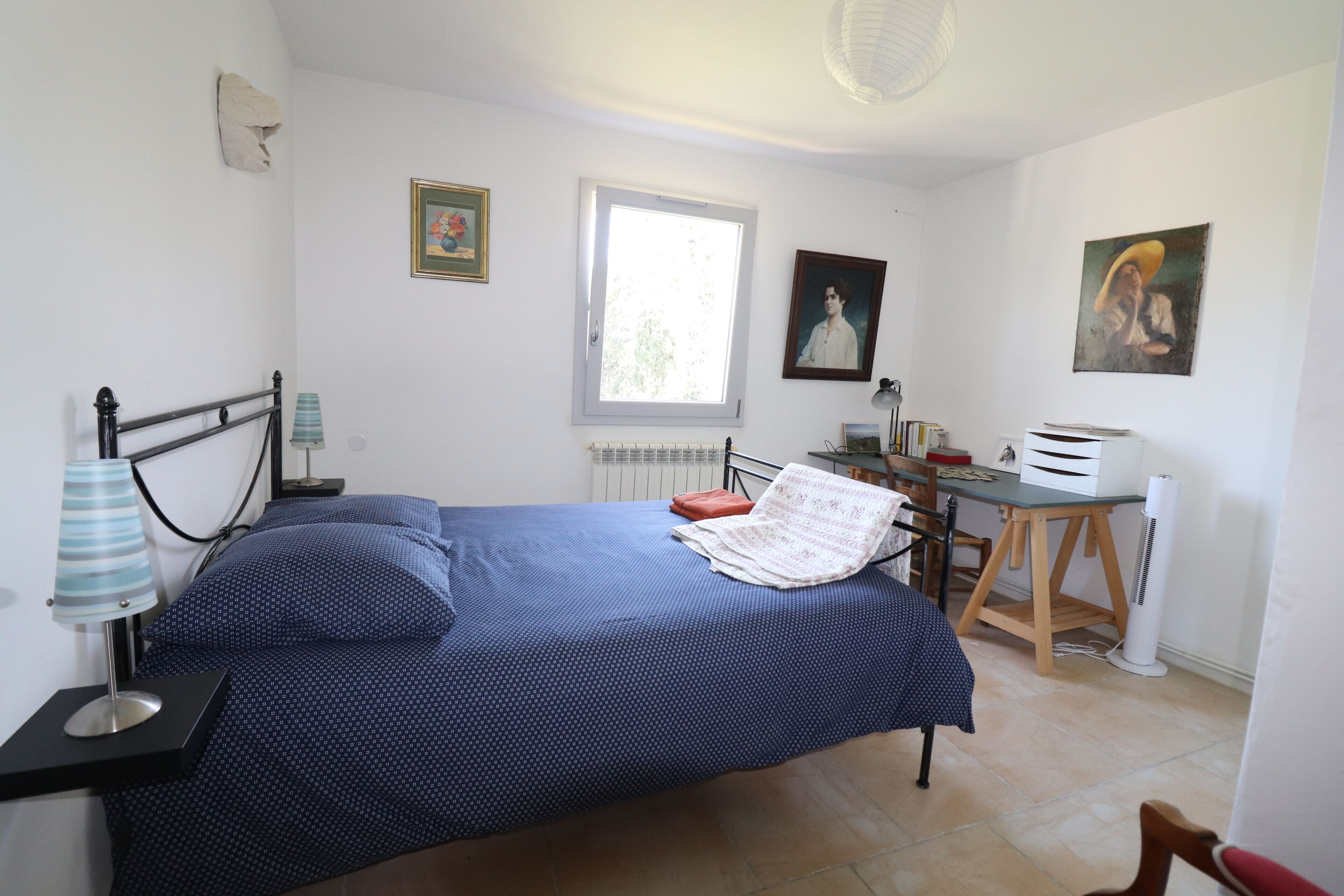 A bedroom with a bed, a desk, a chair, a lamp, and a radiator.