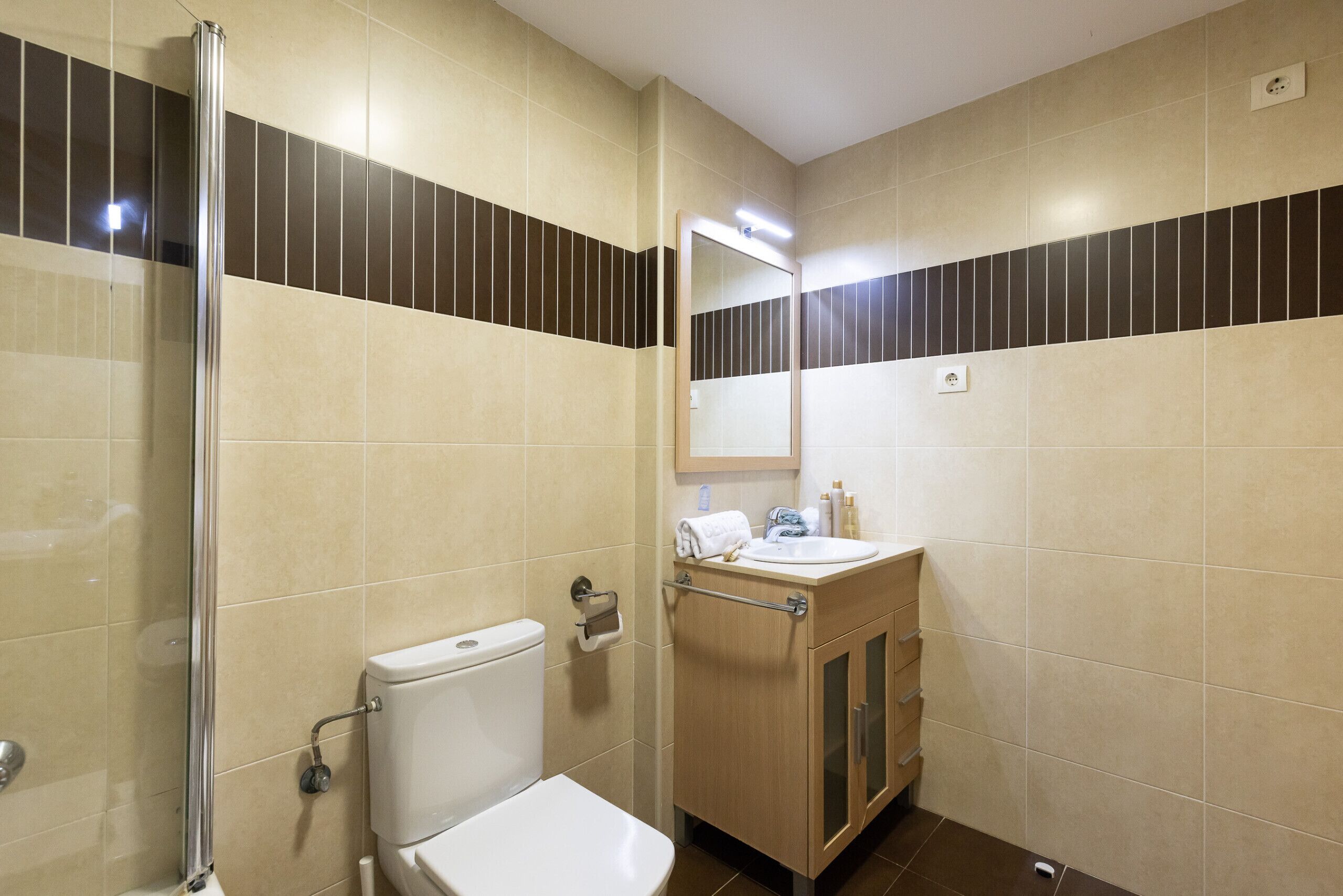 Un baño con inodoro, lavamanos, espejo y ducha.