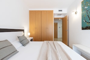 Ein Hotelzimmer mit Bett, Nachttisch, Lampe, Kleiderschrank und einem Bild an der Wand.