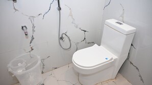 Un baño con inodoro, ducha y cubo de basura.
