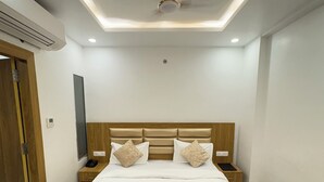 Una habitación de hotel moderna con una cama grande, cabecera de madera, mesitas de noche y un equipo de aire acondicionado.