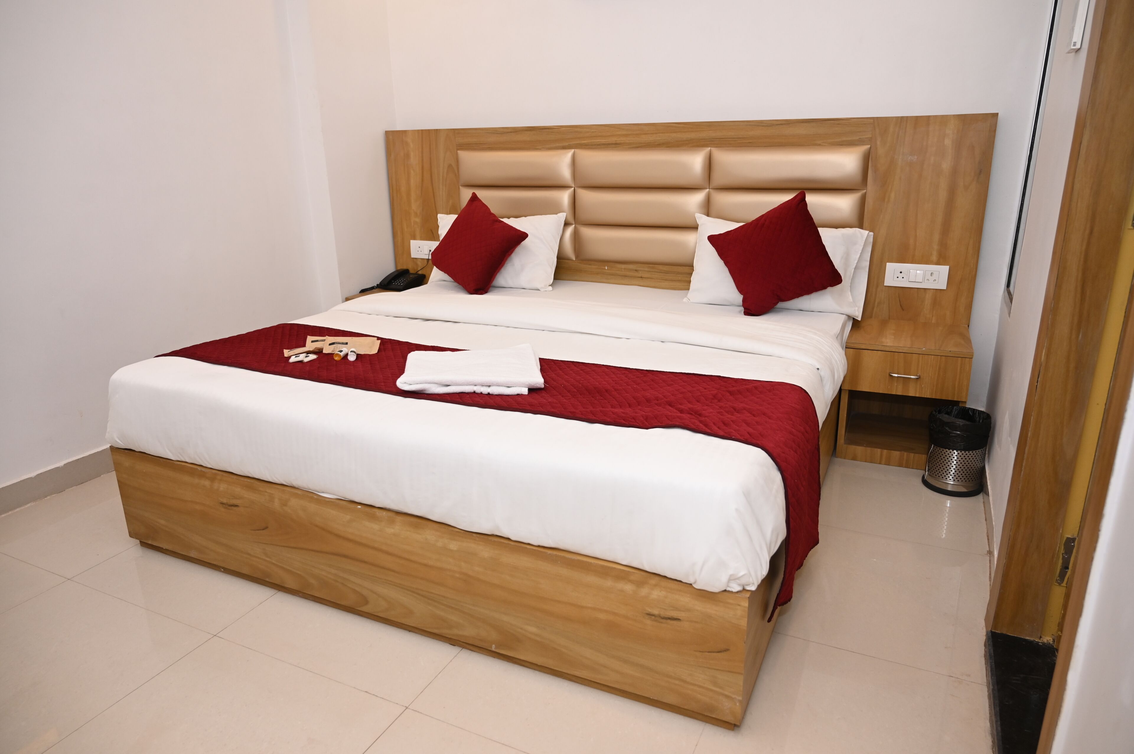 A bed with a wooden headboard, white bedding, and red pillows.
