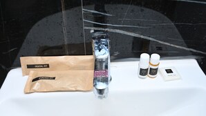 Un lavabo con un kit de higiene bucal, un neceser de afeitado y dos botes de crema de afeitar.