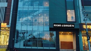 Un hotel llamado 'Golden Bliss' con una fachada moderna de vidrio, un letrero que indica 'Habitaciones & Banquetes', y una escalera visible que lleva a la entrada.