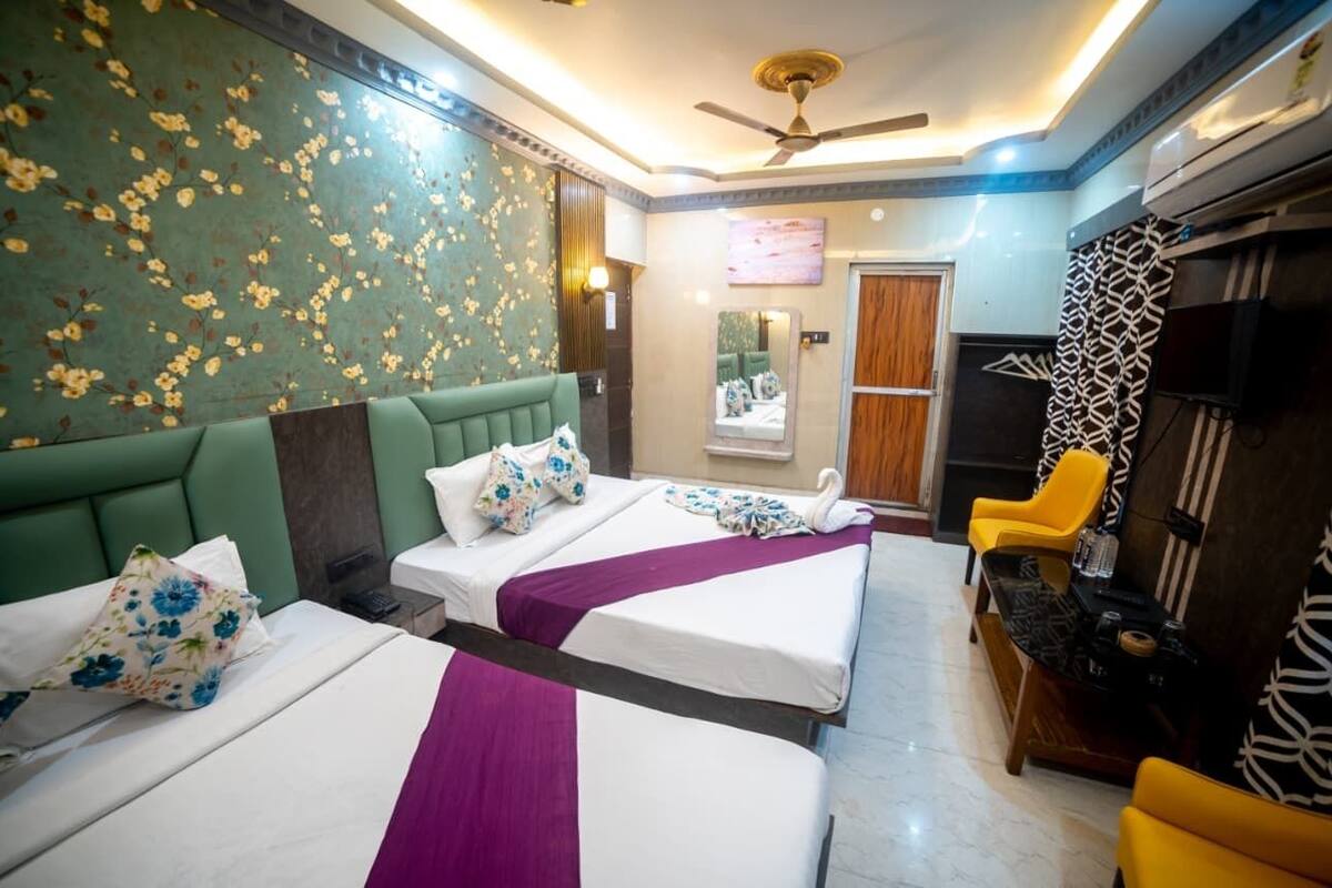 Habitación de hotel con dos camas, un sofá, un televisor y un ventilador de techo.