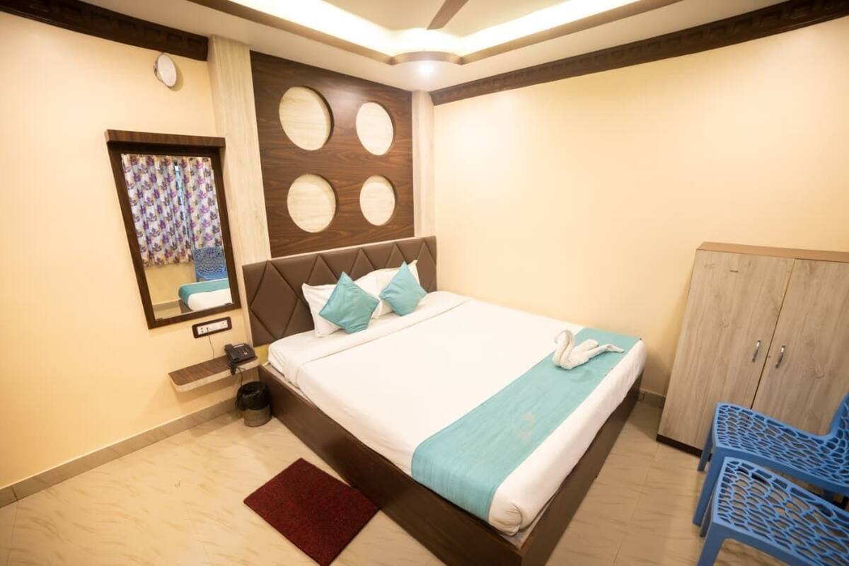 Una habitación de hotel con una cama, un espejo, un armario y una silla azul.