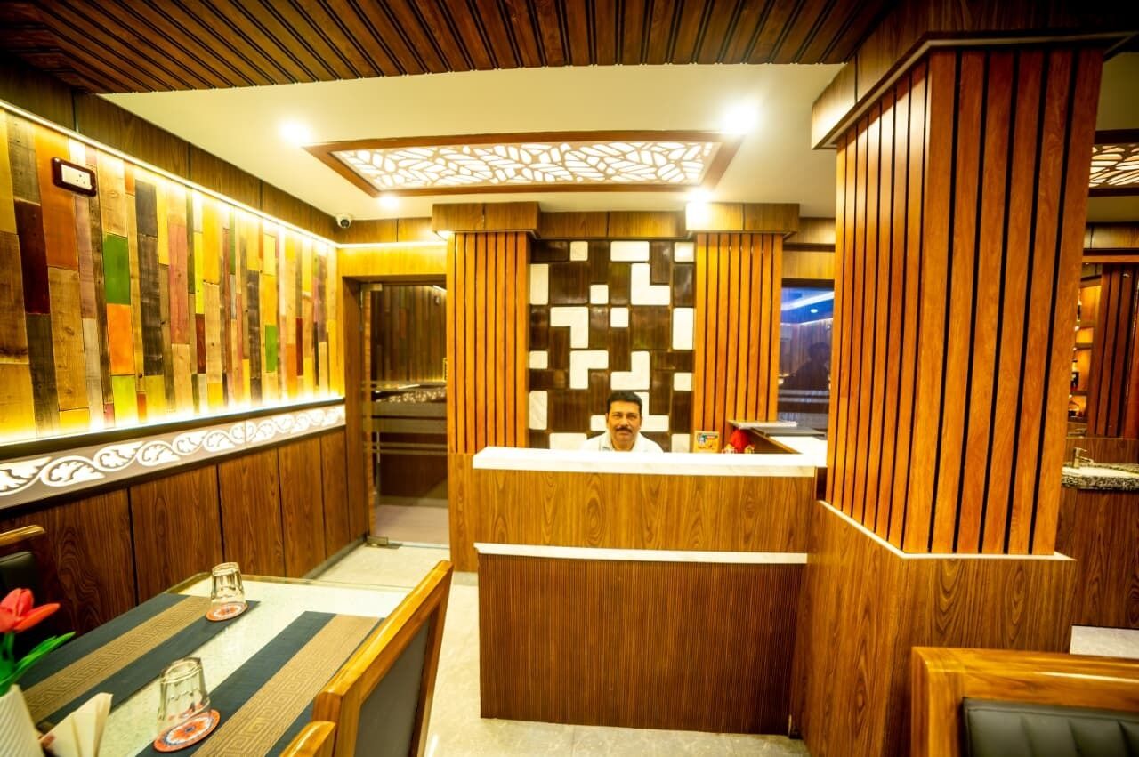 A reception area with a wooden reception desk, a patterned wall, and a ceiling with a geometric light fixture.