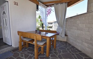 Ein Holztisch und eine Bank in einem Raum mit Steinboden, einer weißen Tür und der Zahl '21' an der Wand.