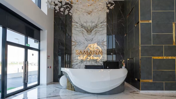 Ein Empfangsschalter mit Marmorwand und goldenen Akzenten, ein modernes Interior-Design und ein Glastür-Eingang.