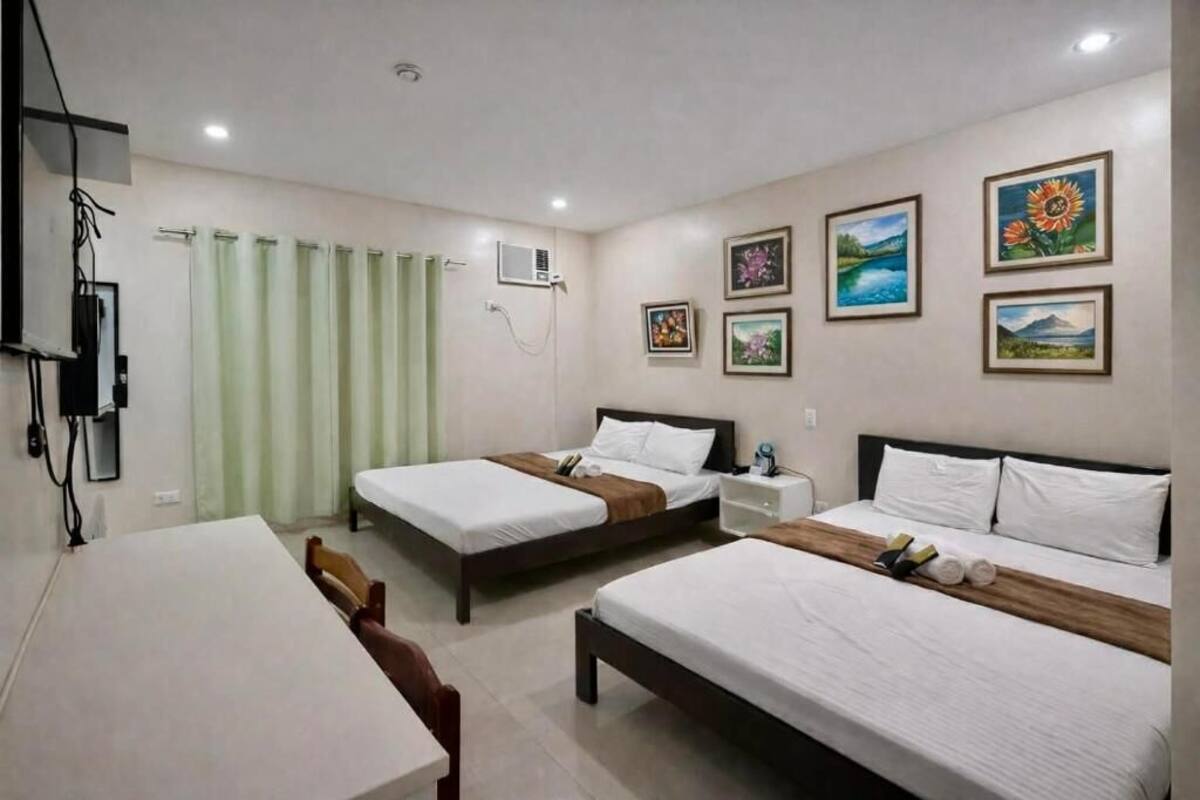 Una habitación de hotel con dos camas, una mesa, una silla y obras de arte en las paredes.