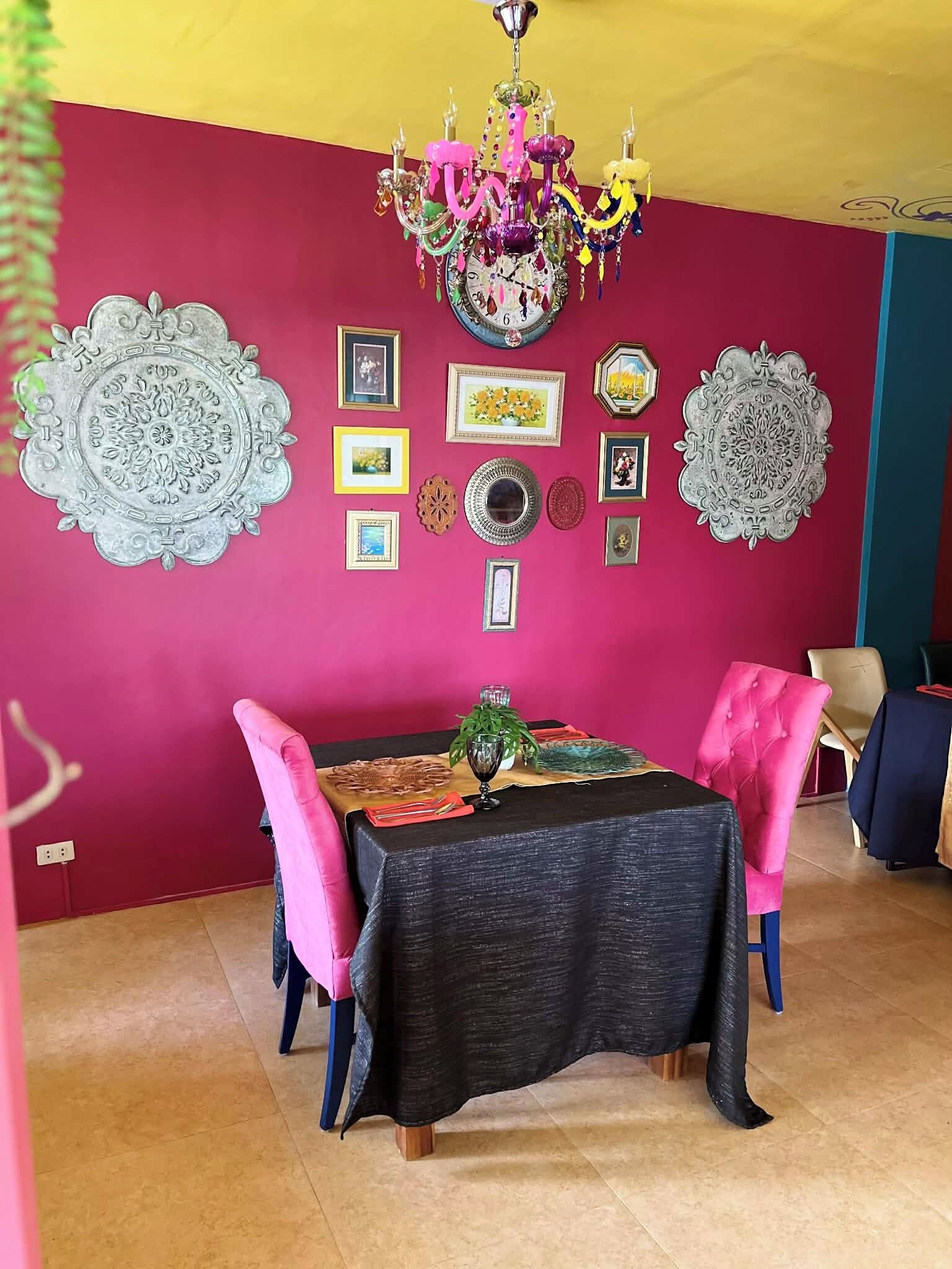 A dining area with a table set for two, a chandelier, and wall decorations.