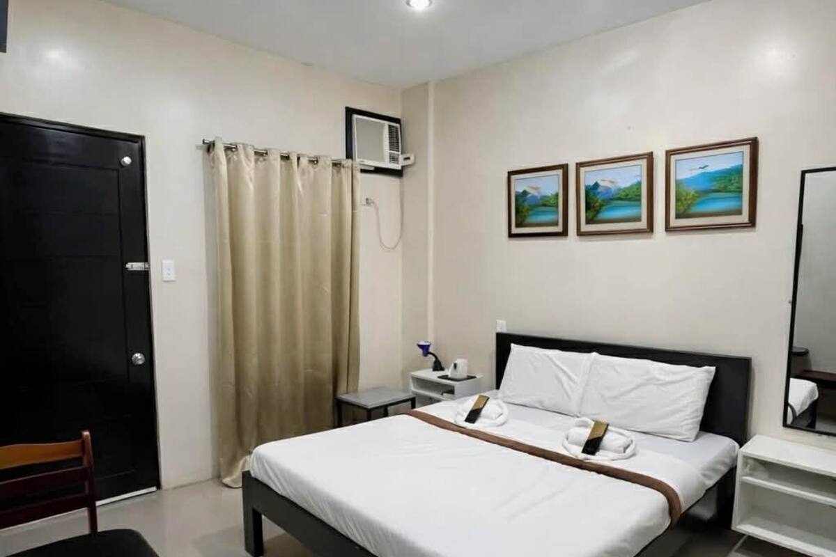 Habitación de hotel con cama, escritorio, silla, ducha y tres cuadros en la pared.