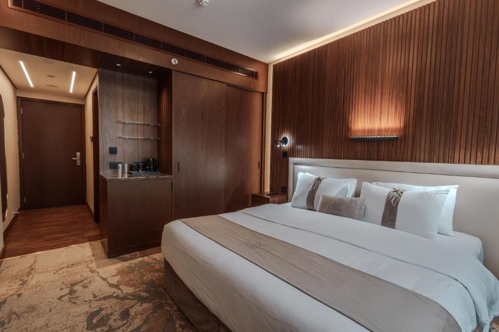 Habitación de hotel con una cama grande, paneles de madera en las paredes, un armario empotrado y una pequeña zona de kitchenette.