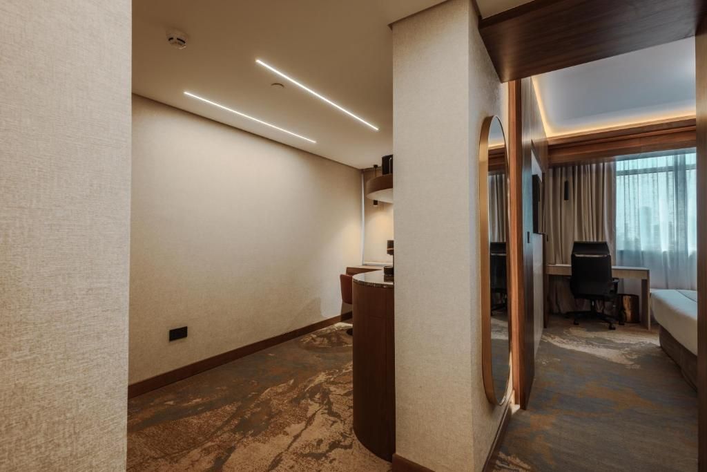 A hotel room with a large mirror, a desk, and a bed.