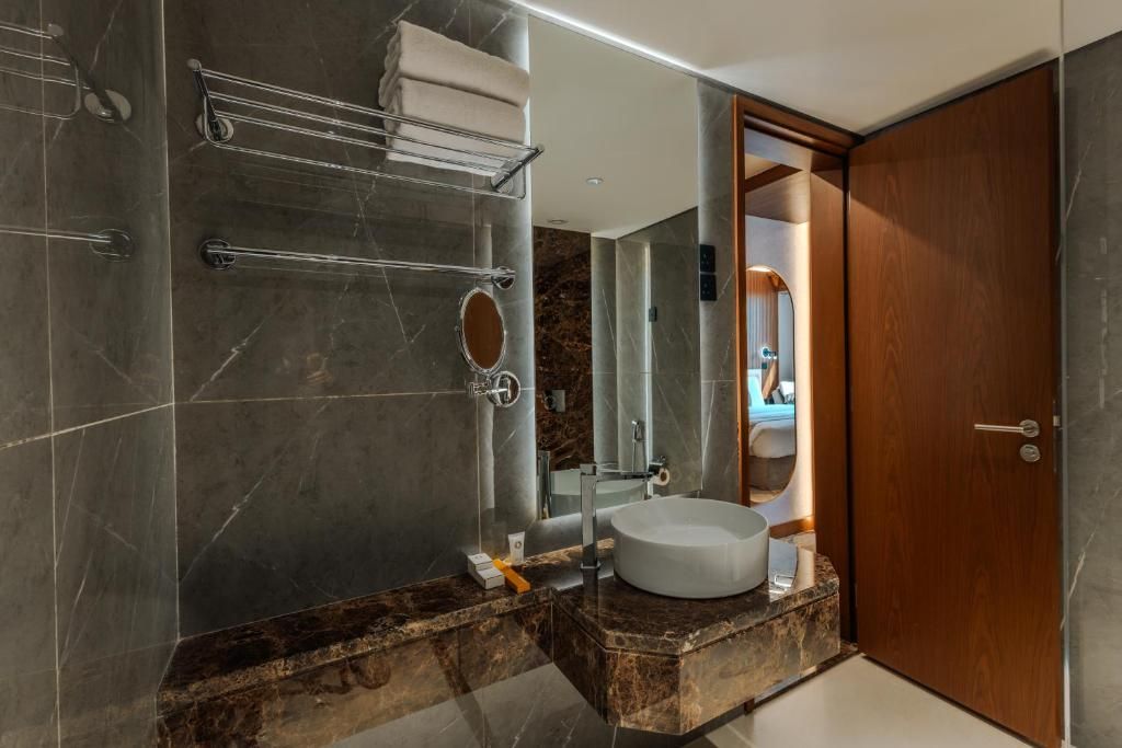 A modern bathroom with a marble vanity, a round mirror, and a built-in sink.