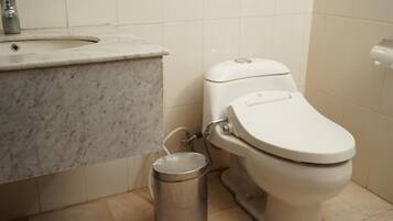 A bathroom with a marble sink, a toilet, and a trash can.