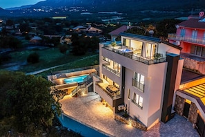 A modern two-story house with a swimming pool, outdoor seating, and a view of the surrounding landscape. - Exclusive dream villa with pool, whirlpool, sauna and wine cellar (Novi Vinodolski)