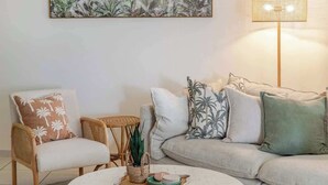 A living room with a round coffee table, a sofa, a chair, a small side table, and a floor lamp. - A Calm City Base Cairns CBD (Cairns North)