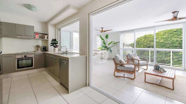A modern kitchen with a dining area, large windows, and a ceiling fan. - A Calm City Base Cairns CBD (Cairns North)